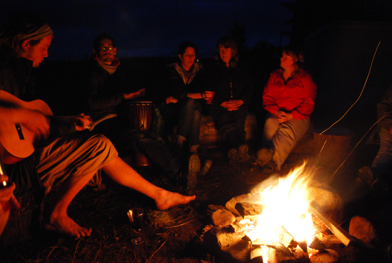 People gathered around a fire at Rubha Phoil on the Isle of Skye, playing guitar and djembe, sharing music and connection under the night sky